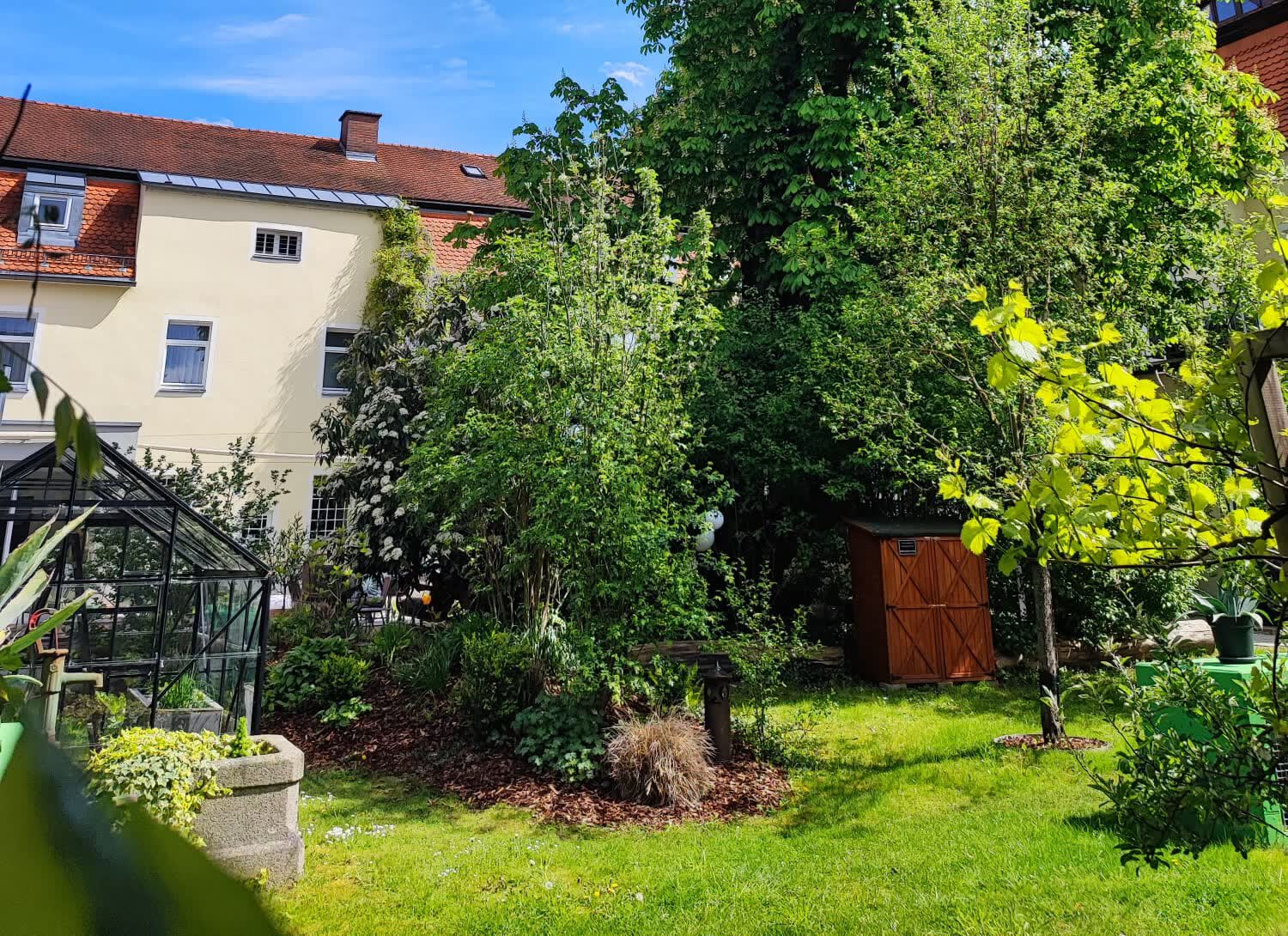 Der Hofgarten mit Gewächshaus, Obstbäumen und Hochbeeten